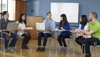 Graduate students sitting at desks collaborating.